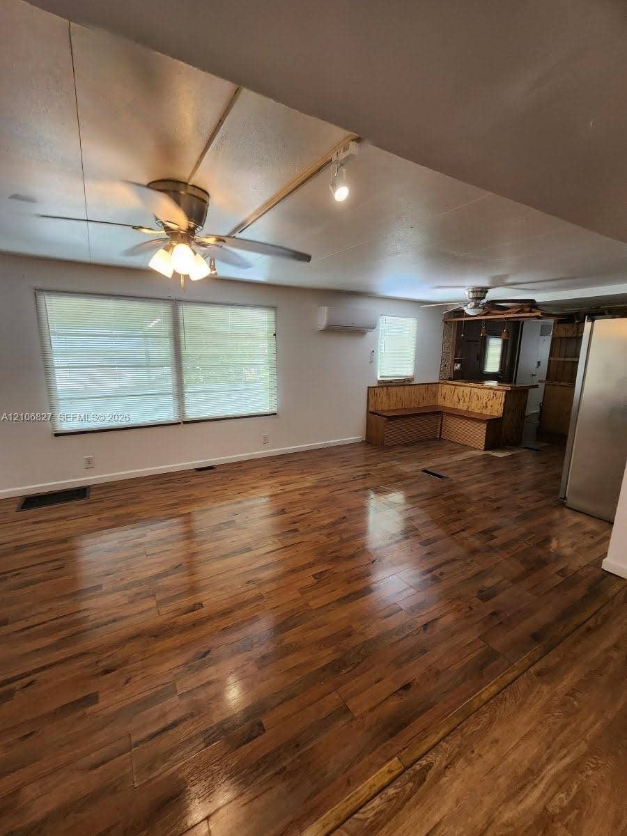 Wood-finish flooring, dual ceiling fans with integrated lighting, wall-mounted climate control unit, and built-in L-shaped bench seating