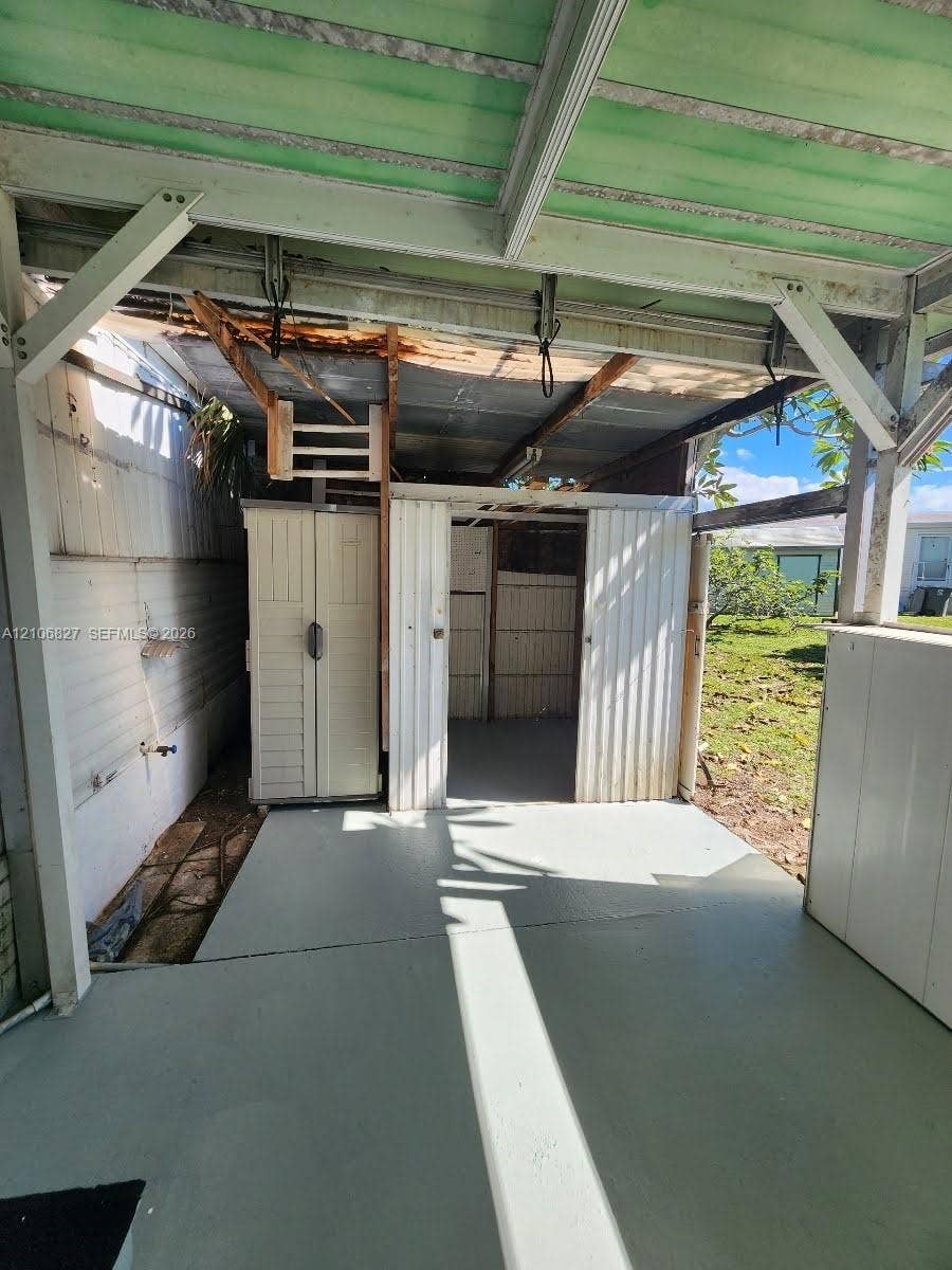 Covered outdoor space featuring a concrete floor, corrugated metal roofing, and built-in storage structures