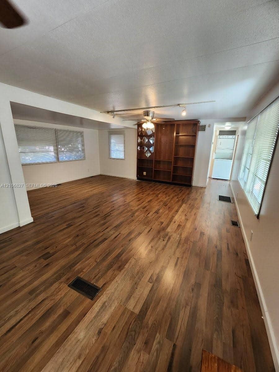 Living area featuring wood-finish flooring, built-in wooden shelving, a ceiling fan, and horizontal window blinds
