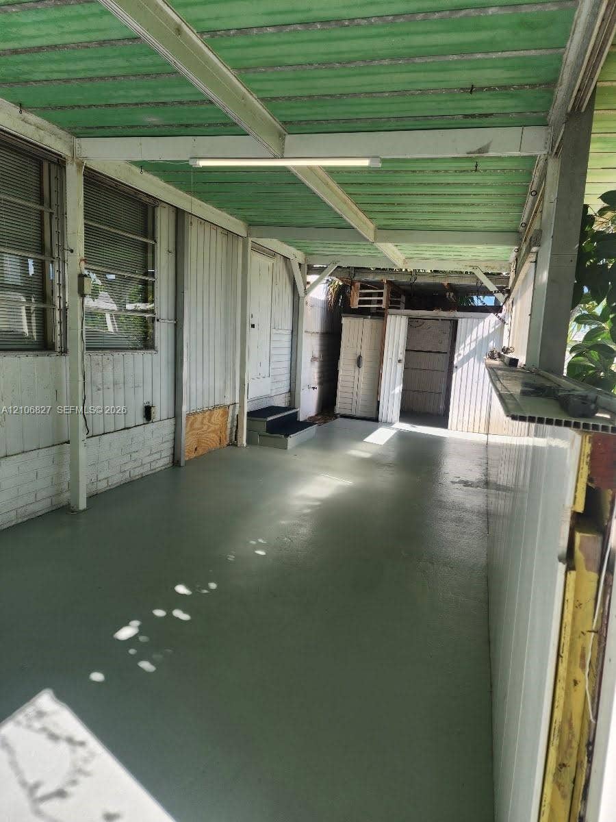 Covered exterior space featuring a solid surface floor, vertical siding, and a built-in storage structure