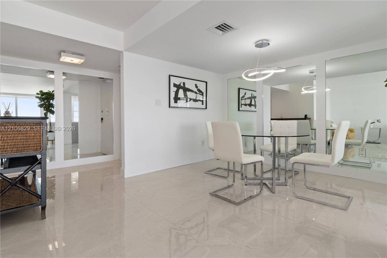 Polished tile flooring, wall-to-wall mirrored panels, and a modern circular LED pendant light fixture