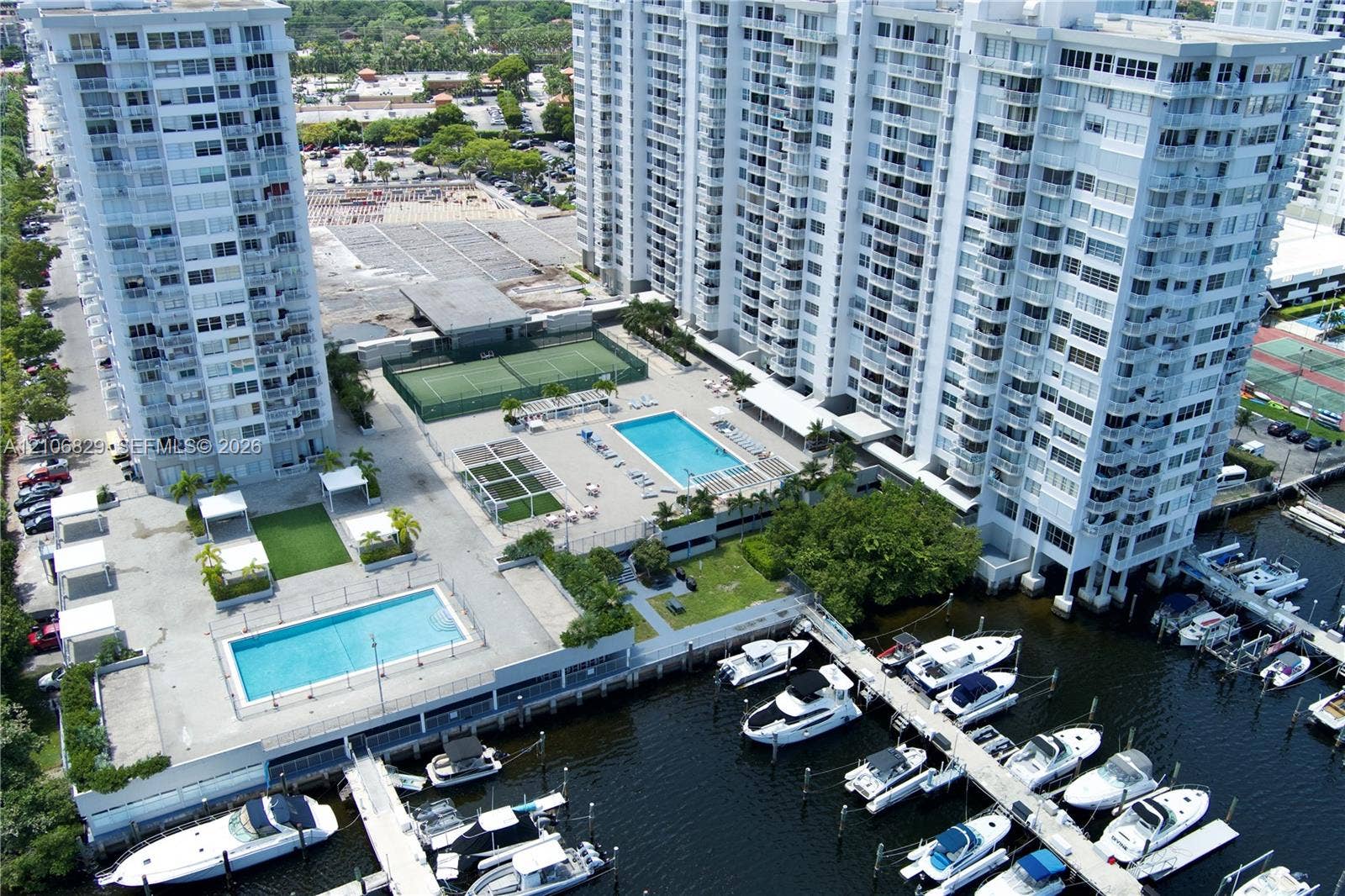 High-rise residential complex featuring multiple swimming pools, tennis courts, and a deep-water marina with private boat slips