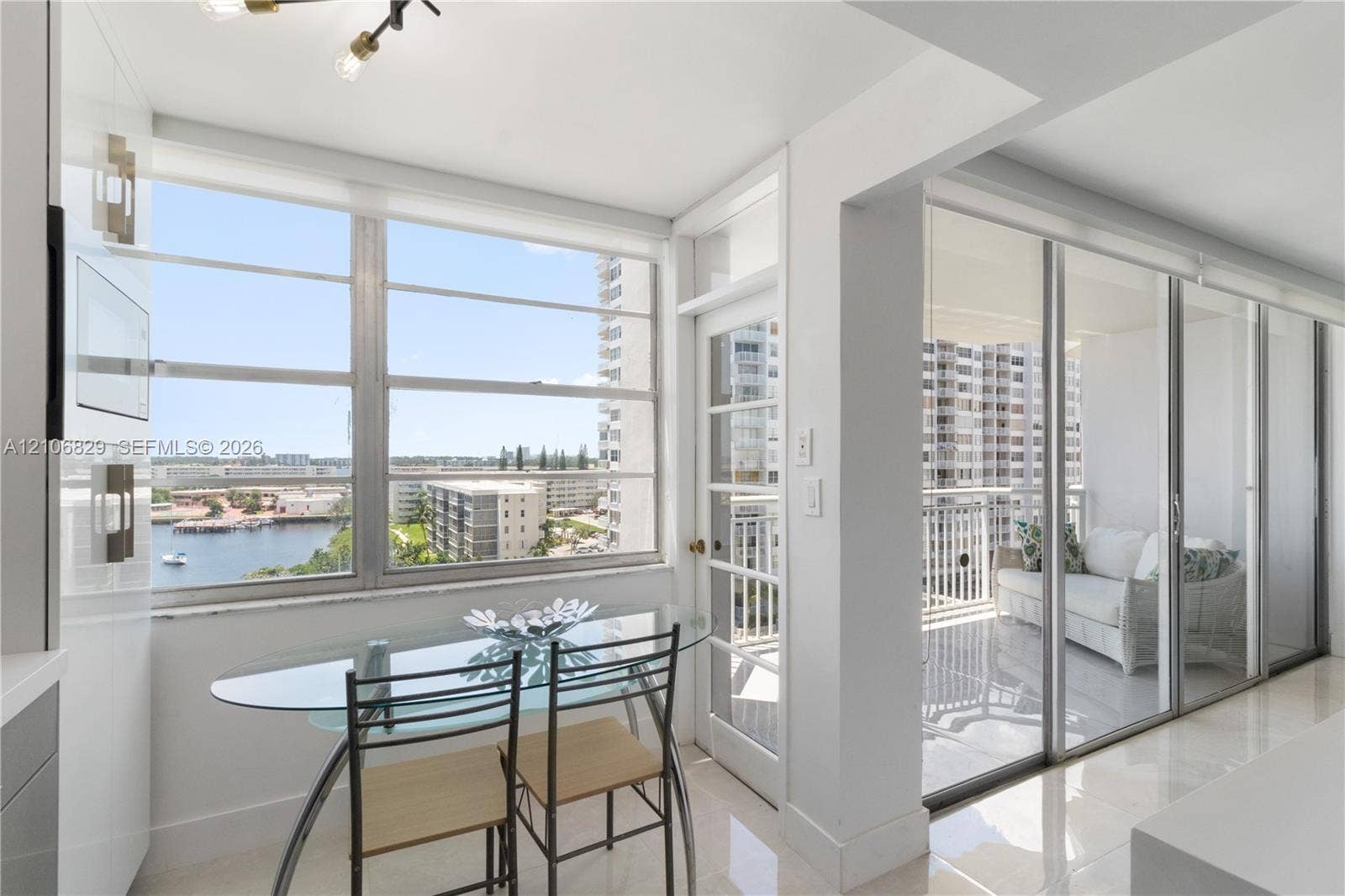 Floor-to-ceiling windows, polished tile flooring, white cabinetry, integrated glass-paned door, and sliding glass balcony access