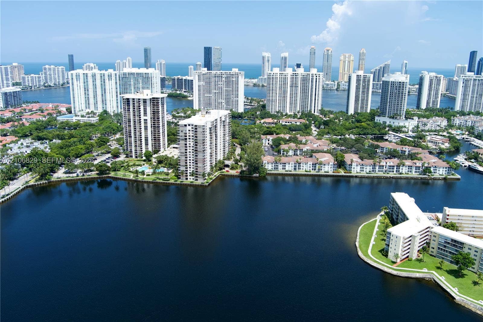 Aerial perspective of a coastal metropolitan area featuring expansive waterways, high-rise residential structures, dense urban landscaping, and oceanfront exposure
