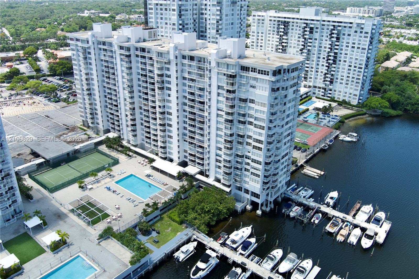 High-rise residential complex featuring a swimming pool, tennis courts, and a private marina with deep-water boat slips
