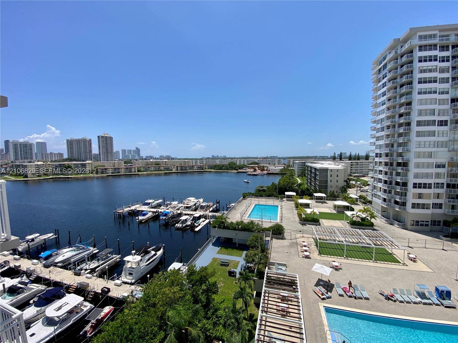 Waterfront terrace overlooking a private marina, community swimming pool, and landscaped courtyard with pergola structures
