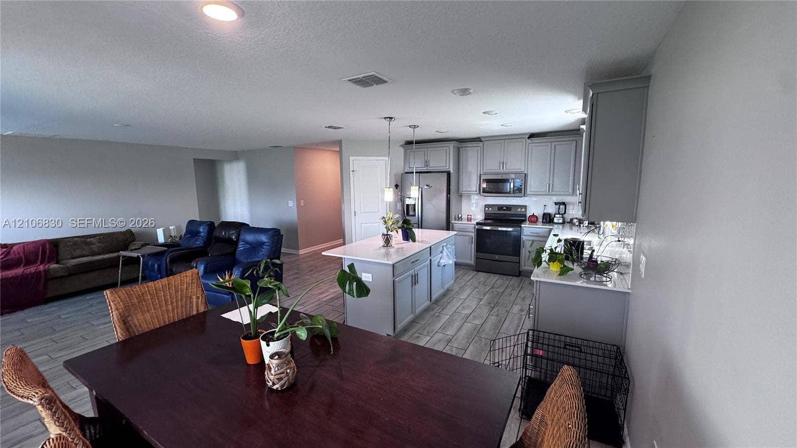 Kitchen featuring a central island with a stone-finish countertop, grey cabinetry, stainless steel appliances, recessed lighting, and wood-finish tile flooring
