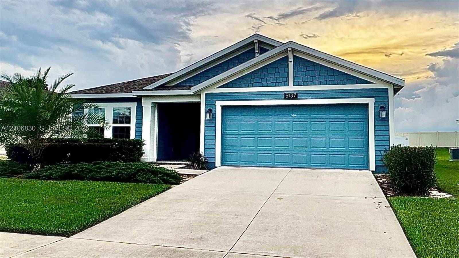 Single-story residence featuring blue horizontal lap siding, shingle-style gable detailing, a two-car garage, and a concrete driveway