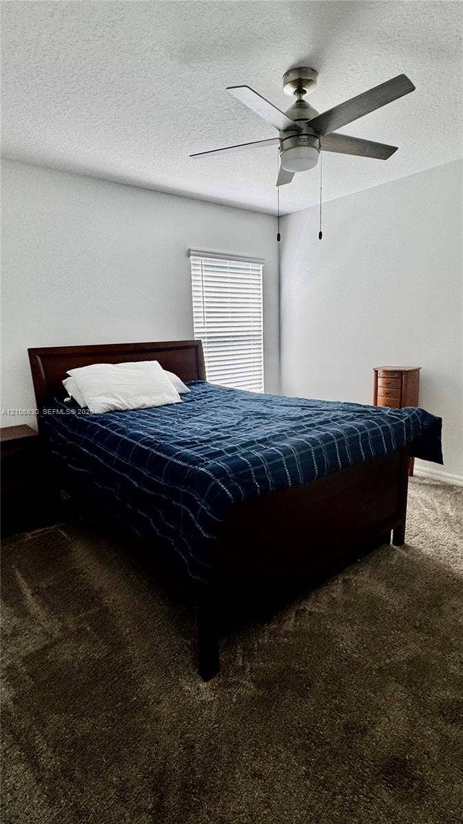 Neutral-toned walls, plush wall-to-wall carpeting, brushed-nickel ceiling fan with integrated lighting, and horizontal window blinds