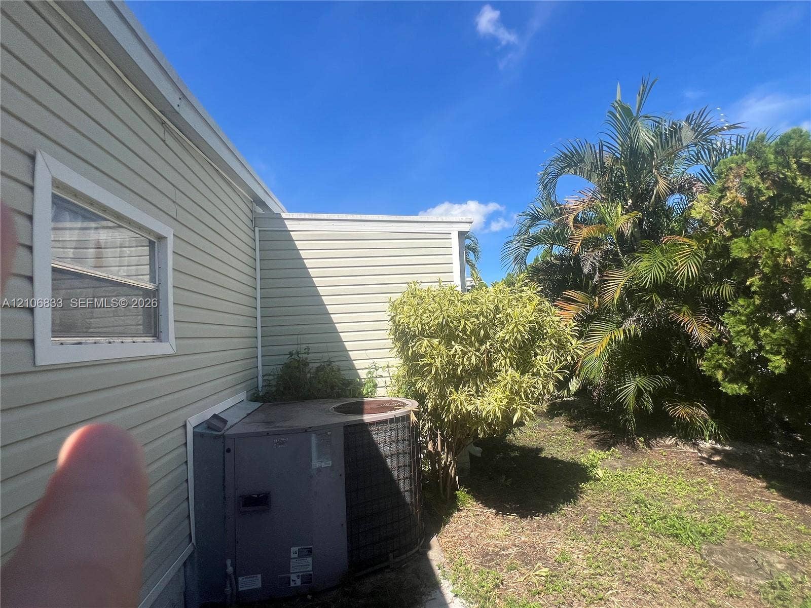 2782 E Marina Drive, Dania Beach, FL 33312 Light-colored horizontal siding, single-hung window with white trim, and exterior HVAC unit