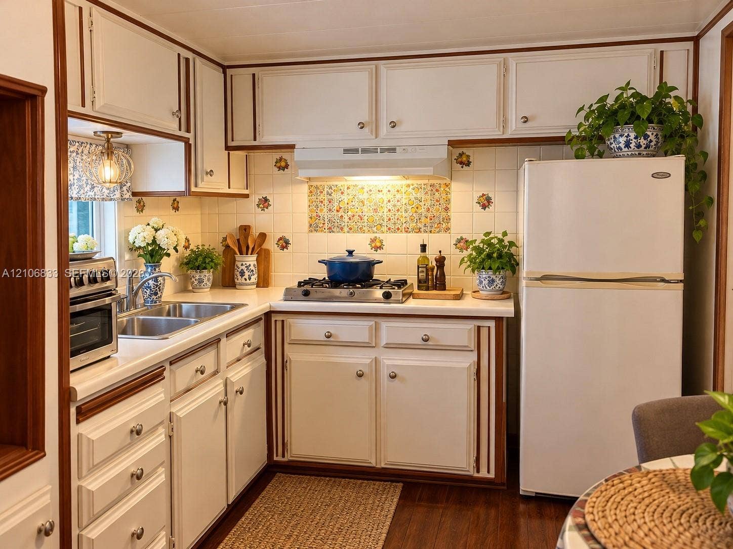 2782 E Marina Drive, Dania Beach, FL 33312 Kitchen featuring white cabinetry with wood trim, decorative tile backsplash, stainless steel double-basin sink, and a four-burner gas cooktop