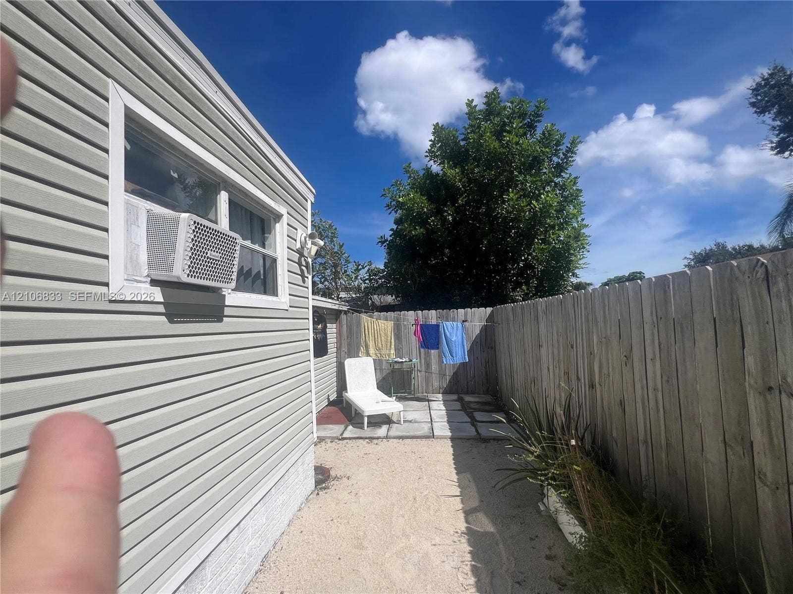 2782 E Marina Drive, Dania Beach, FL 33312 Exterior side yard featuring horizontal vinyl siding, a paved stone patio area, and a wood privacy fence