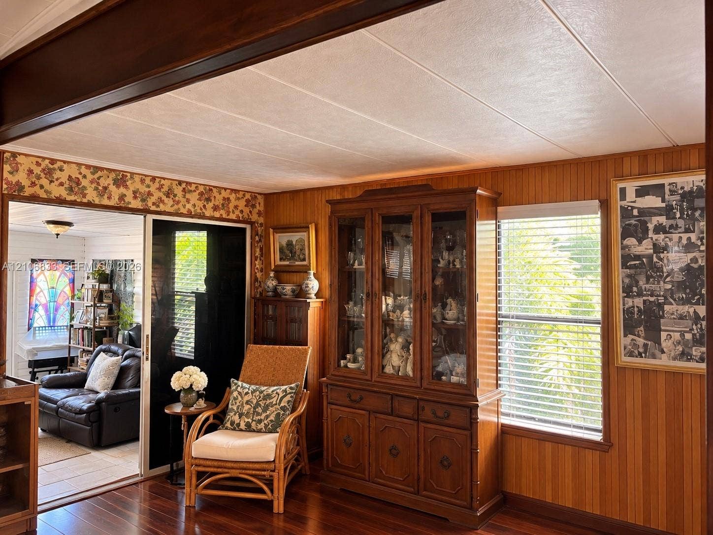 2782 E Marina Drive, Dania Beach, FL 33312 Interior room featuring vertical wood paneling, wood-finish flooring, a dark timber ceiling beam, and a sliding glass door