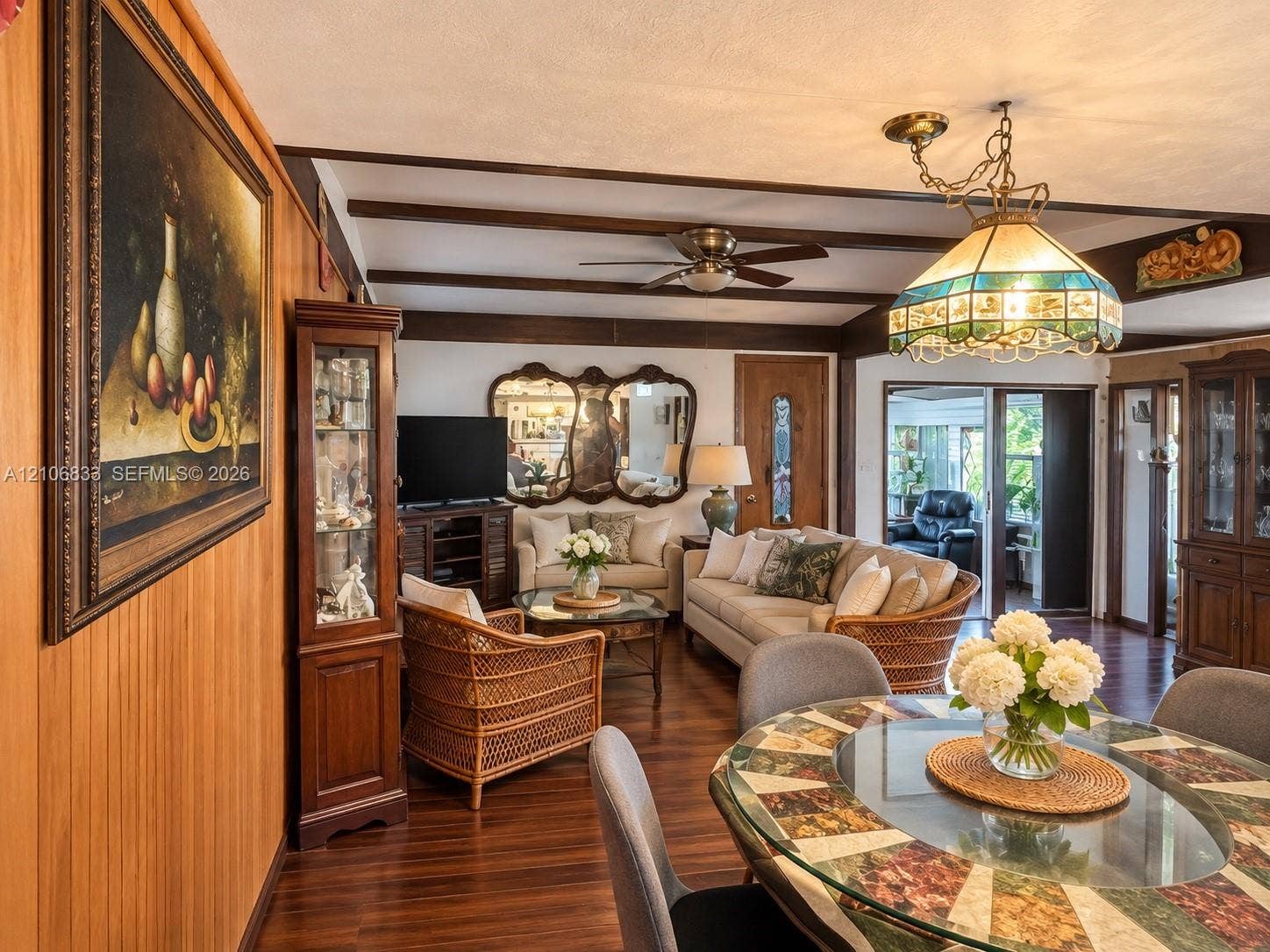 2782 E Marina Drive, Dania Beach, FL 33312 Wood-finish flooring, exposed ceiling beams, stained wood wall paneling, stained glass hanging light fixture, and integrated ceiling fan