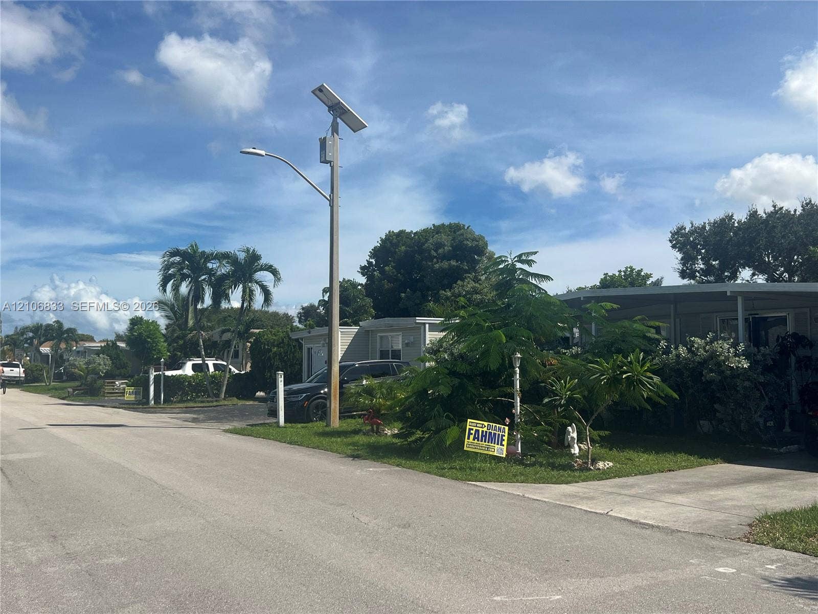 2782 E Marina Drive, Dania Beach, FL 33312 Exterior view featuring a concrete driveway, metal carport, mature landscaping, and an integrated solar-powered light fixture