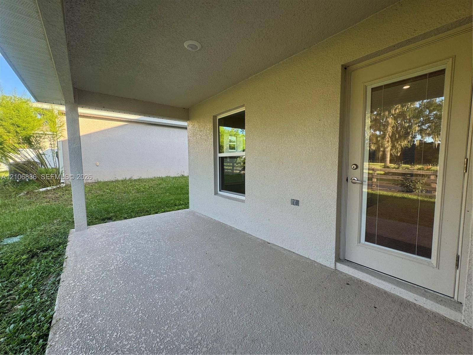 187 NW 45th Loop, Ocala, FL 34475 Covered concrete patio featuring stucco exterior siding, single-hung window, and glass-panel entry door with recessed lighting