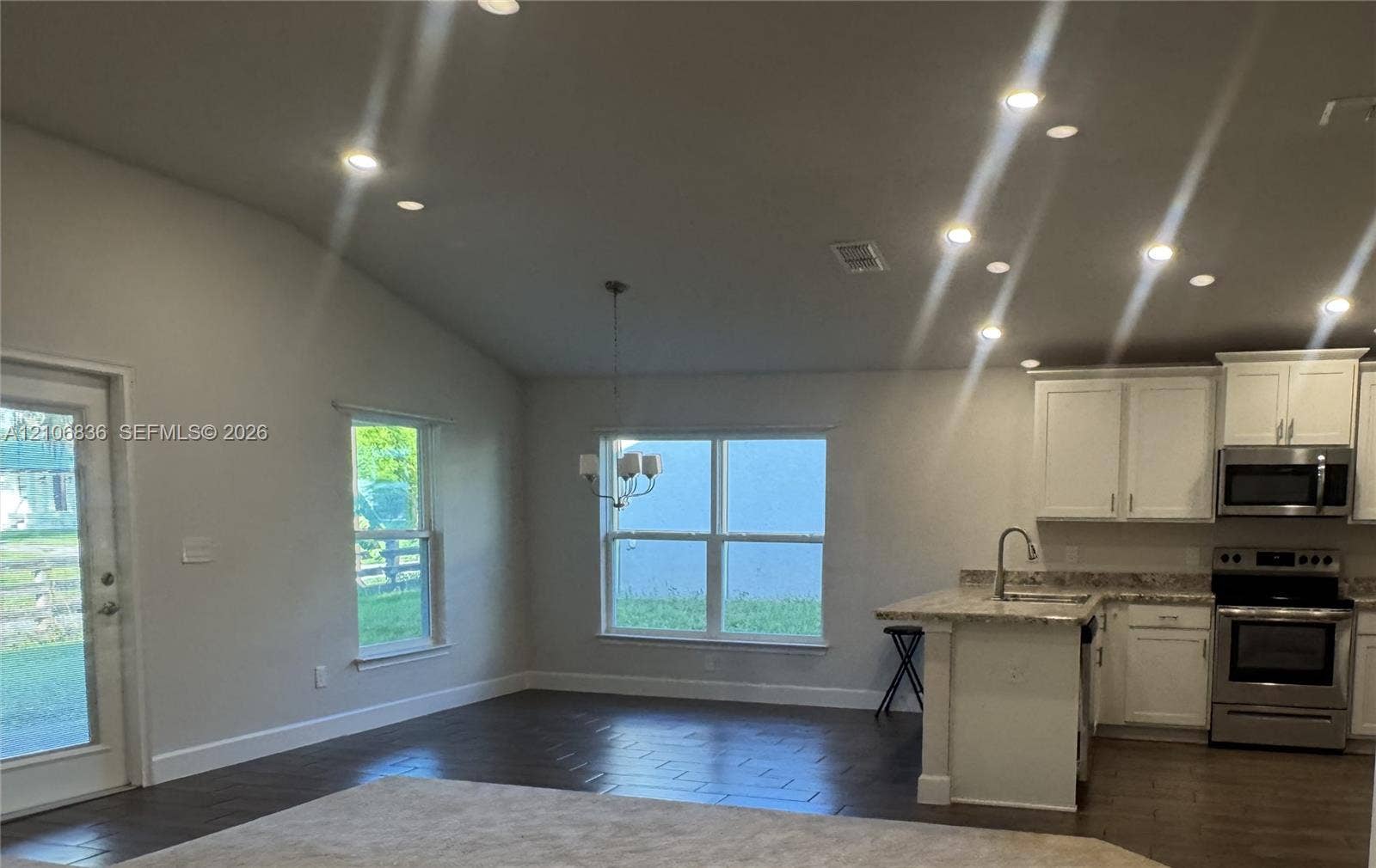 187 NW 45th Loop, Ocala, FL 34475 Vaulted ceilings with recessed lighting, wood-finish flooring, white cabinetry, integrated stainless steel appliances, and multi-paned windows