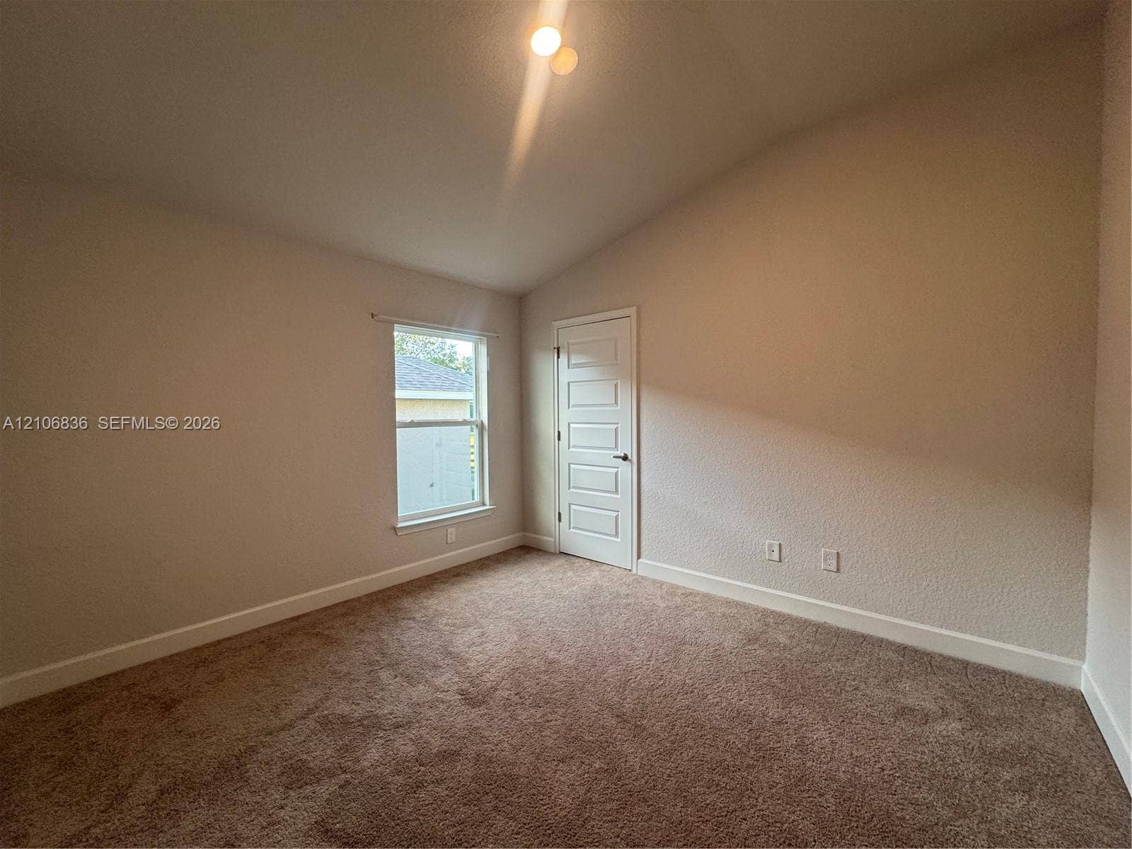 187 NW 45th Loop, Ocala, FL 34475 Vaulted ceiling featuring neutral-toned carpeting, five-panel interior door, and single-pane window