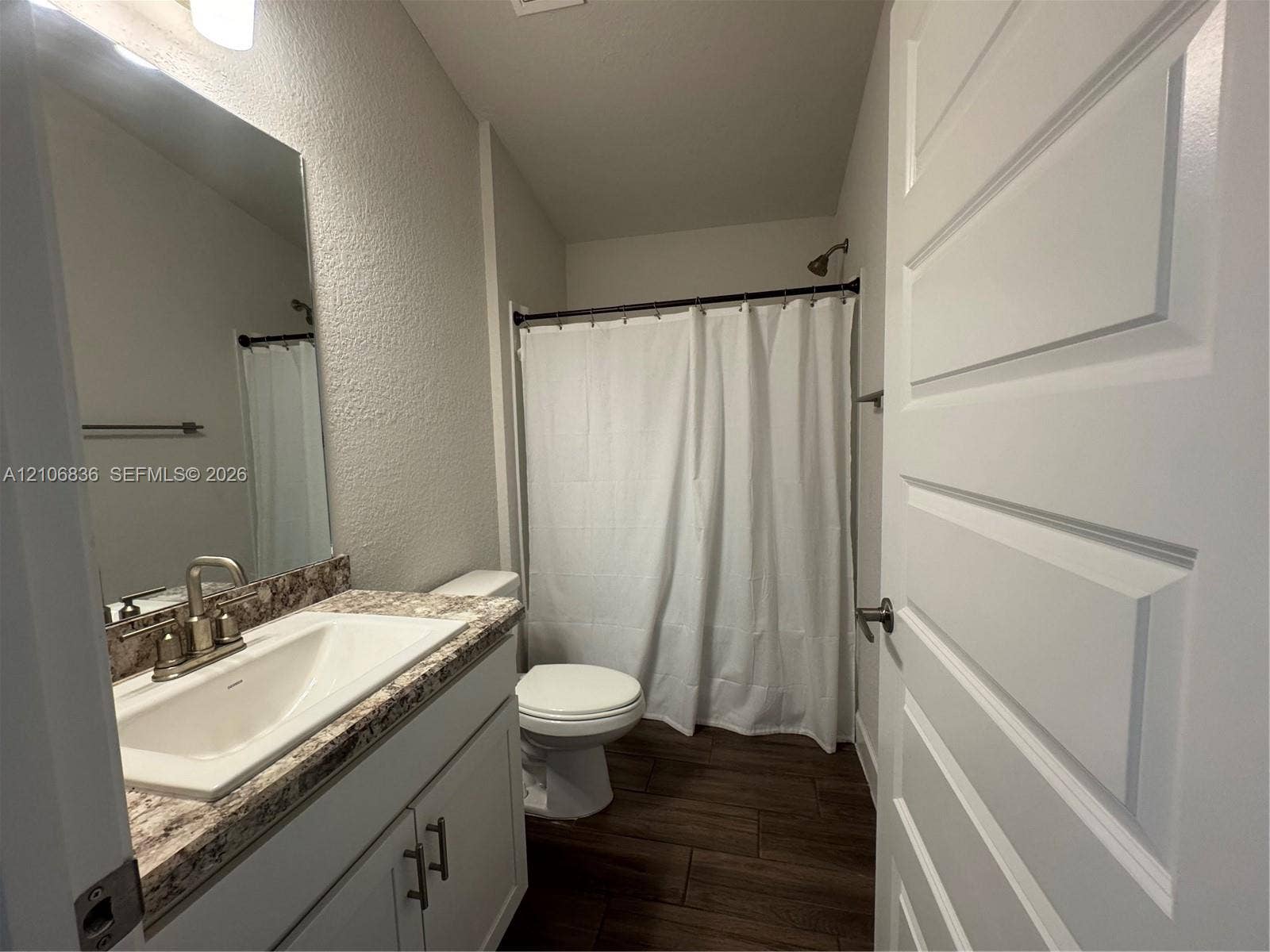 187 NW 45th Loop, Ocala, FL 34475 Bathroom featuring a vanity with a white basin and patterned stone-finish countertop, wood-finish flooring, brushed nickel hardware, and a tub-shower combination