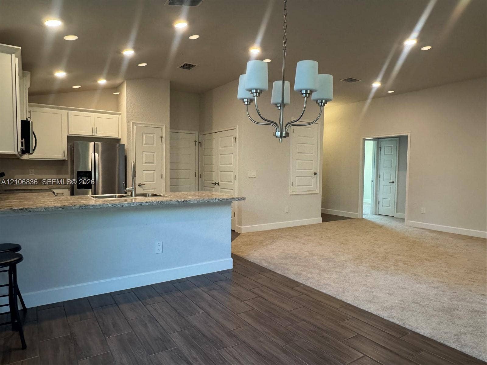 187 NW 45th Loop, Ocala, FL 34475 Kitchen featuring white cabinetry, stone-look countertops, stainless steel refrigerator, recessed lighting, and a multi-arm chandelier