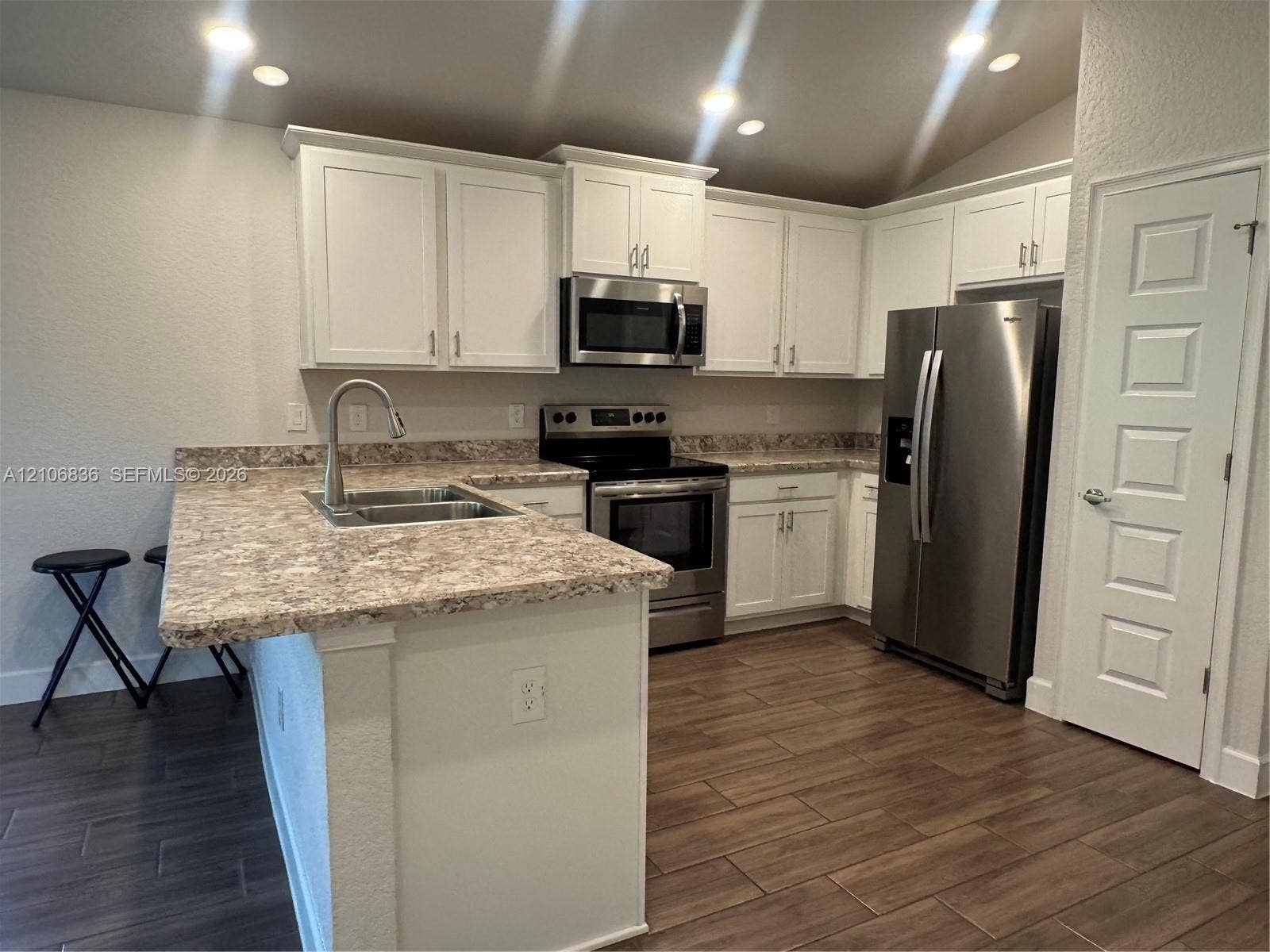 187 NW 45th Loop, Ocala, FL 34475 Kitchen featuring white cabinetry, stone-patterned countertops, stainless steel appliances, a high-arc kitchen faucet, and wood-finish tile flooring