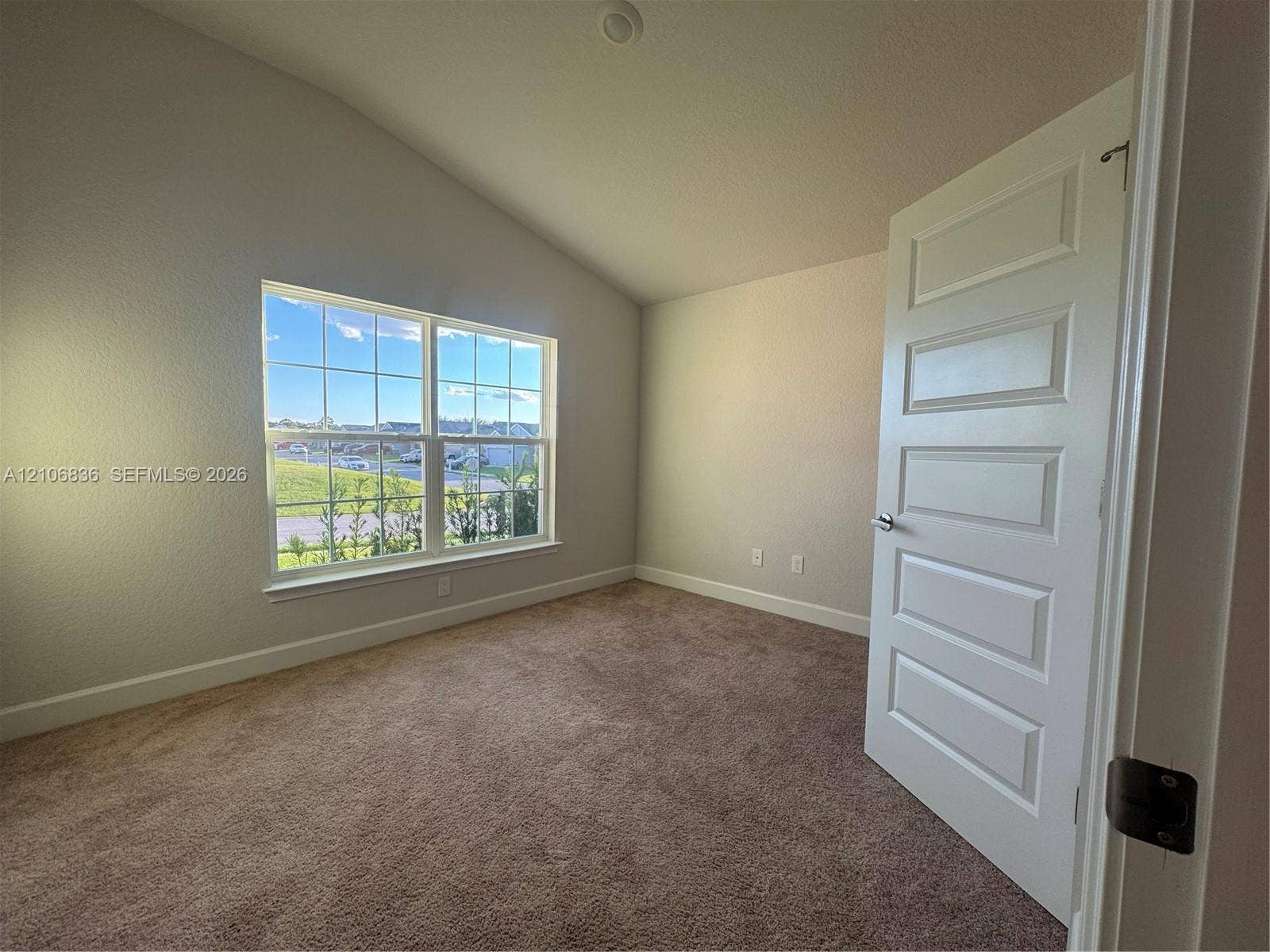 187 NW 45th Loop, Ocala, FL 34475 Vaulted ceiling room featuring neutral-toned carpeting, a five-panel interior door, and a multi-pane window