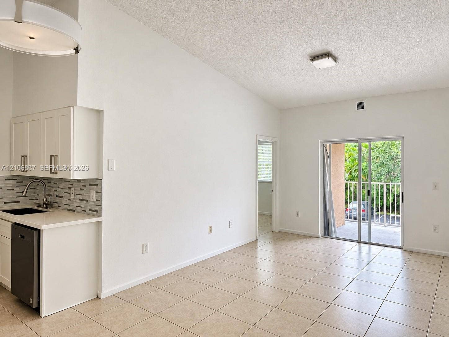 Vaulted ceilings, tiled flooring, glass sliding doors, built-in cabinetry with light-toned countertops, and multi-toned glass tile backsplash
