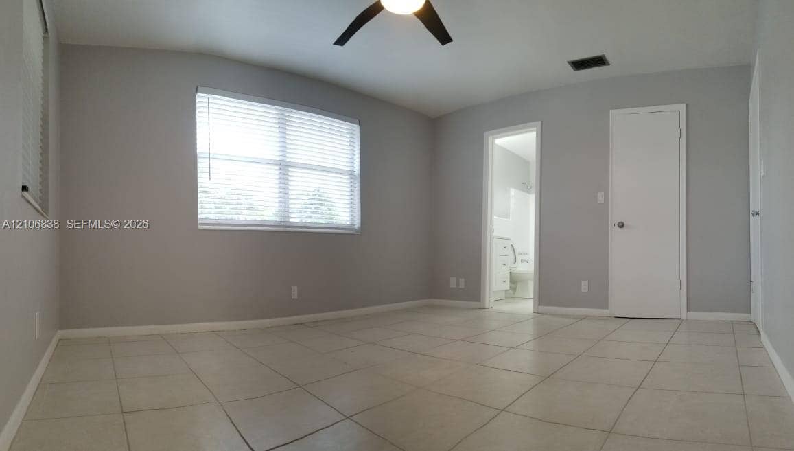Interior space featuring large-format ceramic tile flooring, neutral wall paint, a ceiling-mounted light fixture, and horizontal window blinds