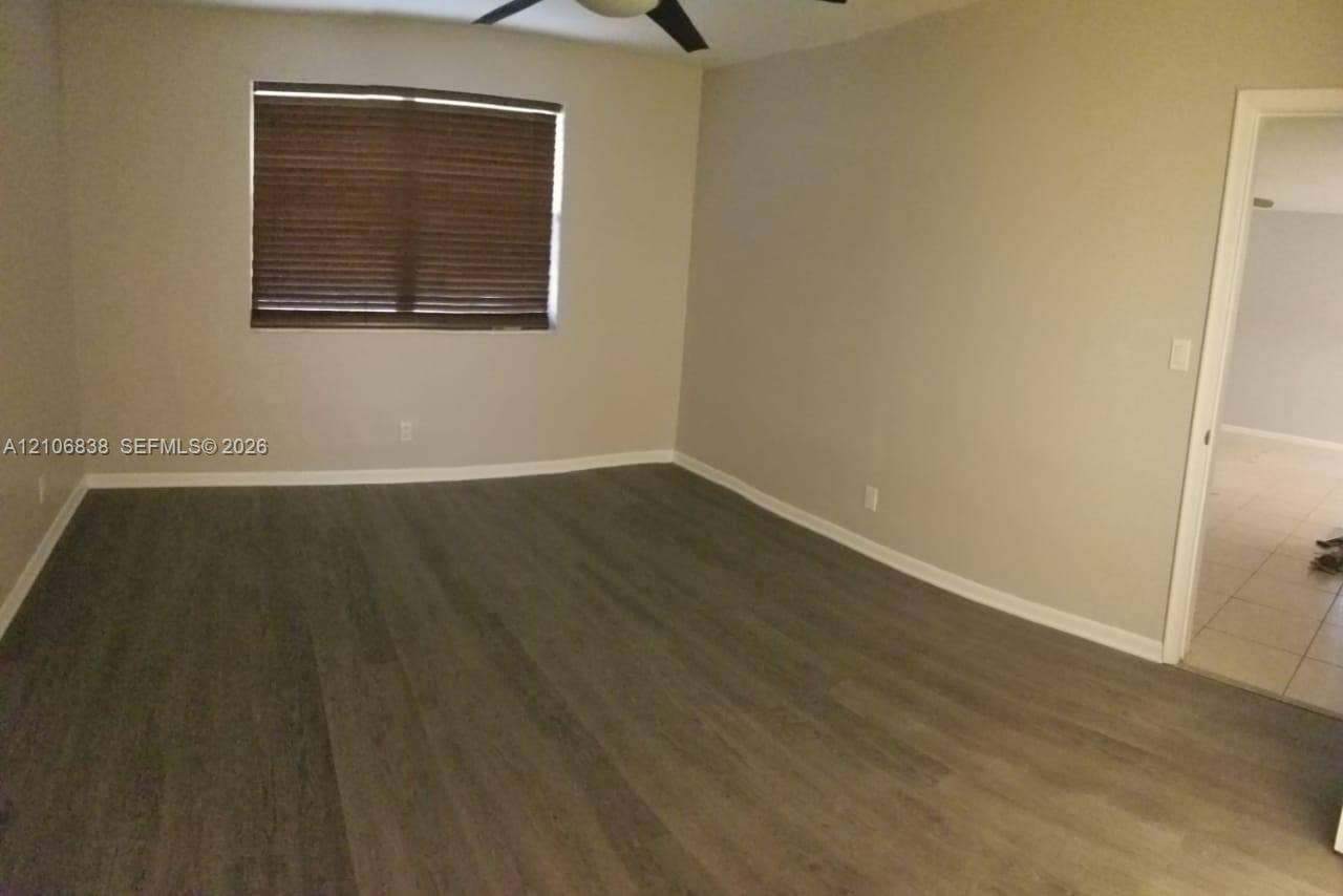 Room featuring wood-finish flooring, neutral wall paint, and a ceiling fan