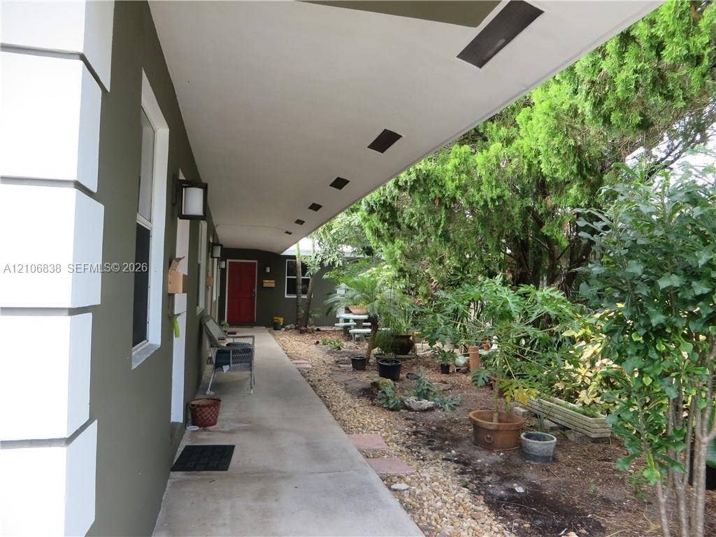 Covered concrete walkway with recessed lighting and exterior wall-mounted fixtures