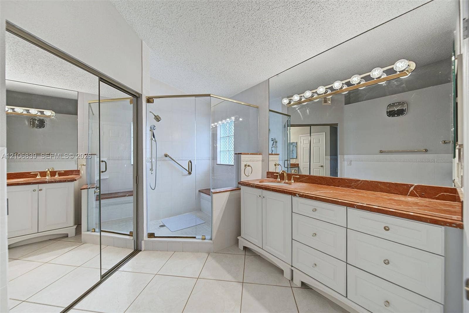 12683 NW 11th Place, Sunrise, FL 33323 Bathroom featuring white cabinetry, stone-finish countertops, a glass-enclosed shower, tile flooring, and wall-to-wall mirrors