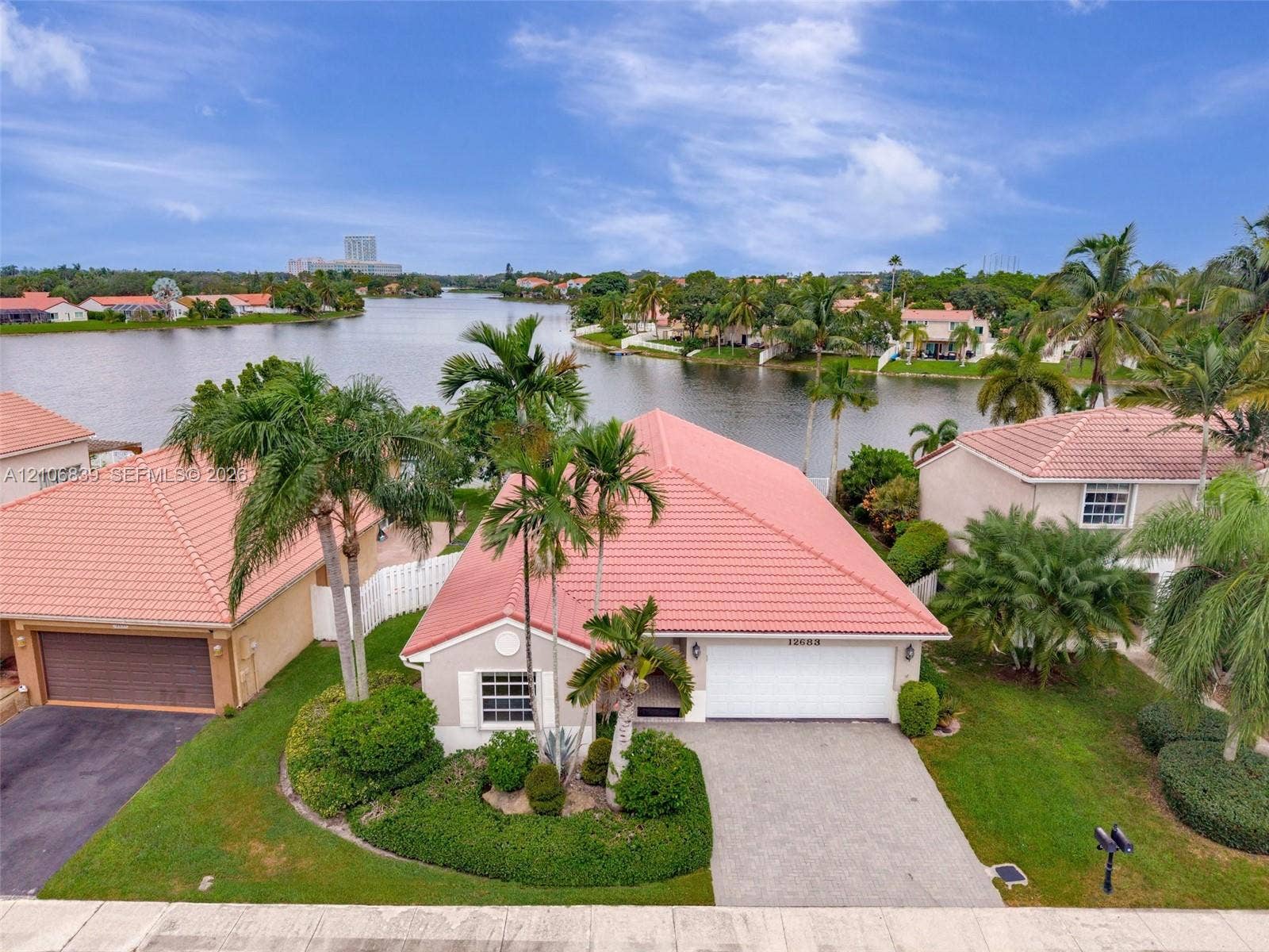 12683 NW 11th Place, Sunrise, FL 33323 Single-story residence featuring a tile roof, paved driveway, two-car garage, manicured landscaping, and waterfront positioning
