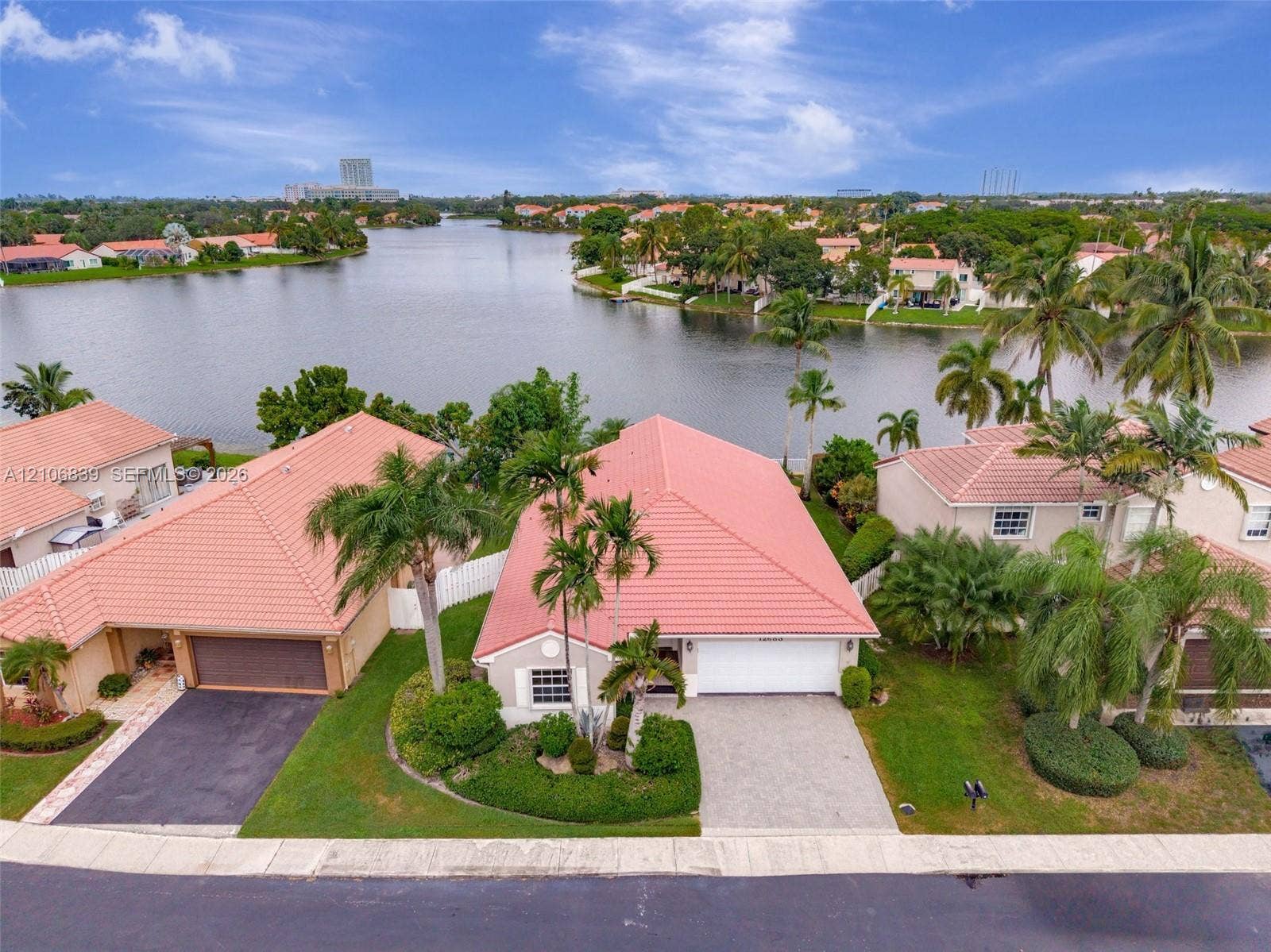 12683 NW 11th Place, Sunrise, FL 33323 Waterfront residence featuring a tile roof, paver driveway, two-car garage, and established landscaping