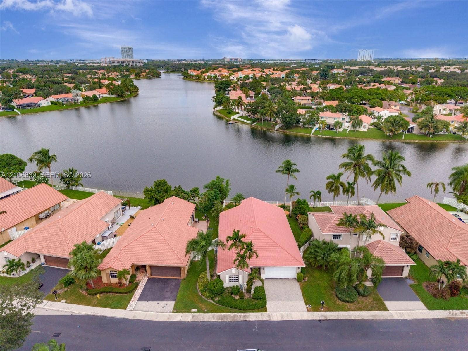 12683 NW 11th Place, Sunrise, FL 33323 Aerial perspective of a waterfront residential enclave featuring terra-cotta tile roofs, paved driveways, manicured landscaping, and mature palm trees