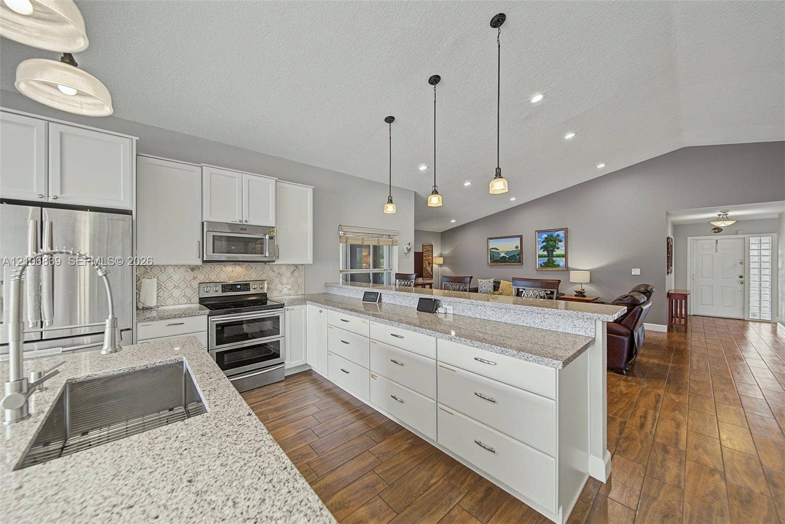 12683 NW 11th Place, Sunrise, FL 33323 Kitchen featuring white shaker-style cabinetry, stone-finish countertops, stainless steel appliances, pendant lighting, and wood-finish flooring