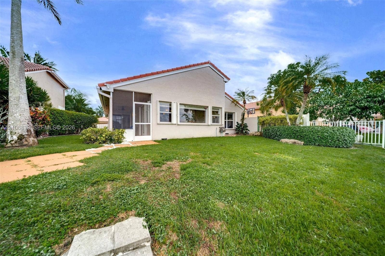 12683 NW 11th Place, Sunrise, FL 33323 Stucco exterior with a tiled roof, featuring a screened-in lanai, concrete walkway, and expansive green lawn