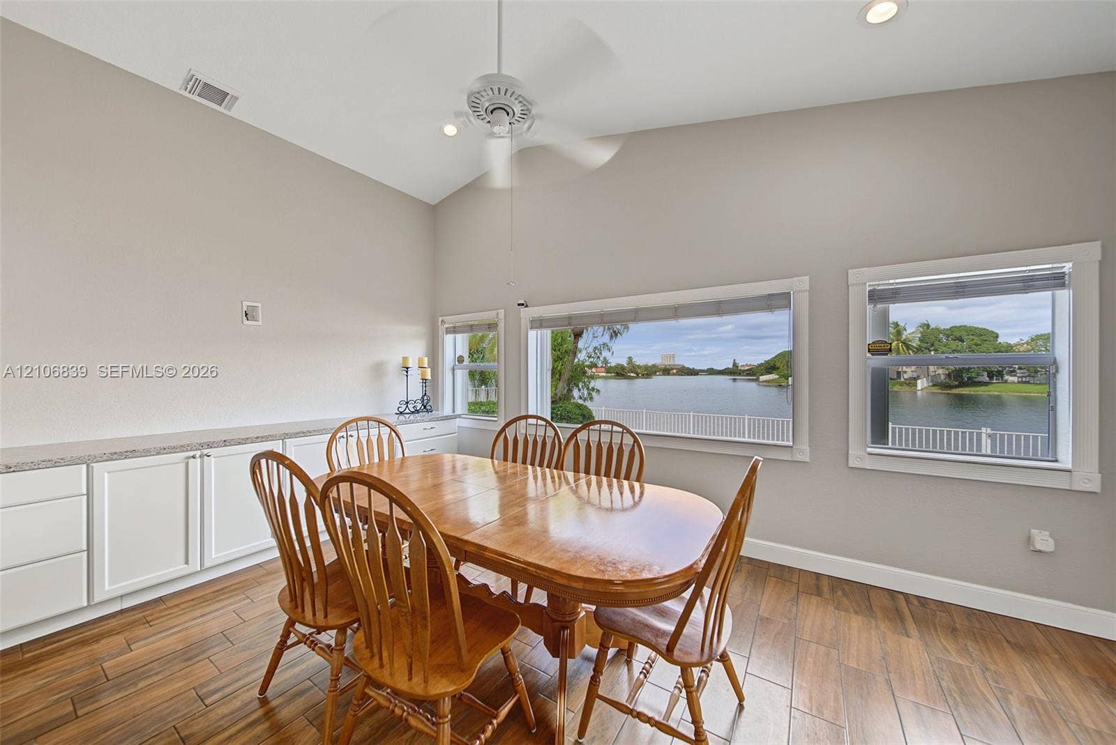 12683 NW 11th Place, Sunrise, FL 33323 Vaulted ceiling featuring a central lighted fan, wood-finish tile flooring, and built-in cabinetry with stone-finish countertops