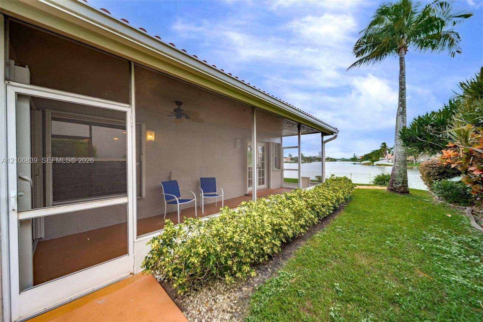 12683 NW 11th Place, Sunrise, FL 33323 Screened-in lanai featuring a ceiling fan, tile flooring, and direct exterior access, complemented by a manicured lawn and water frontage