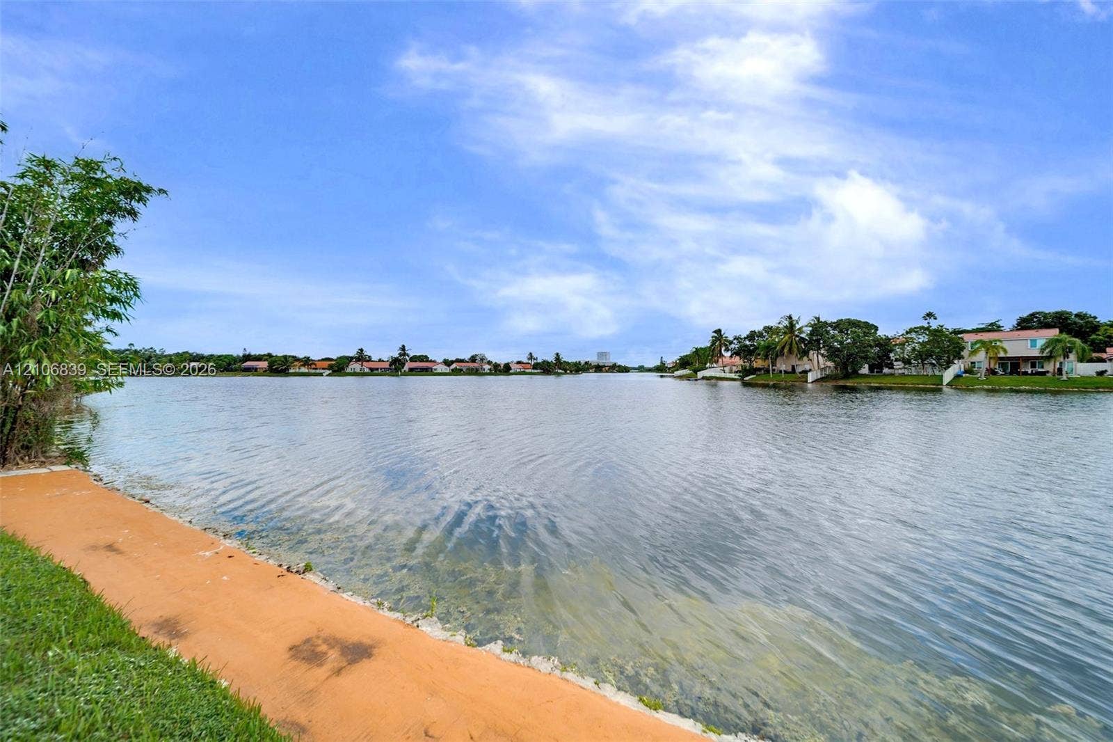 12683 NW 11th Place, Sunrise, FL 33323 Waterfront property featuring a paved walkway, mature landscaping, and an expansive canal backdrop
