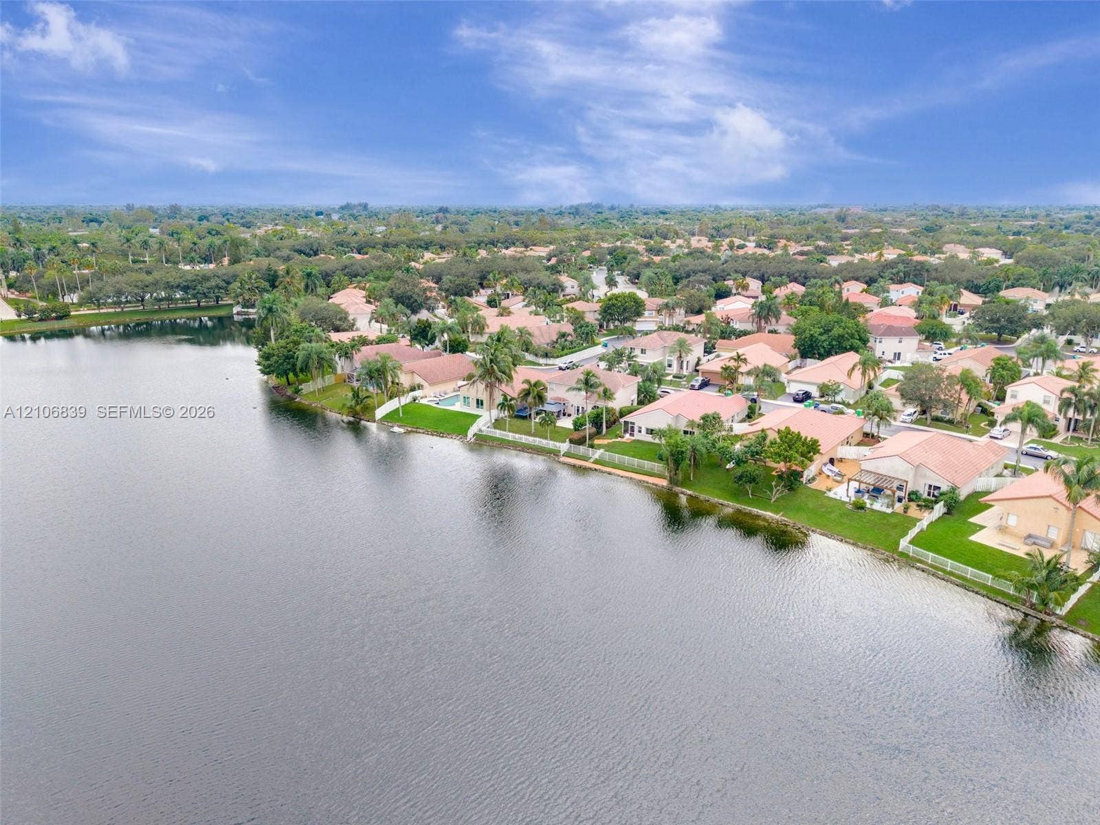 12683 NW 11th Place, Sunrise, FL 33323 Aerial perspective of residential properties featuring waterfront positioning, tiled roofs, manicured lawns, and perimeter fencing
