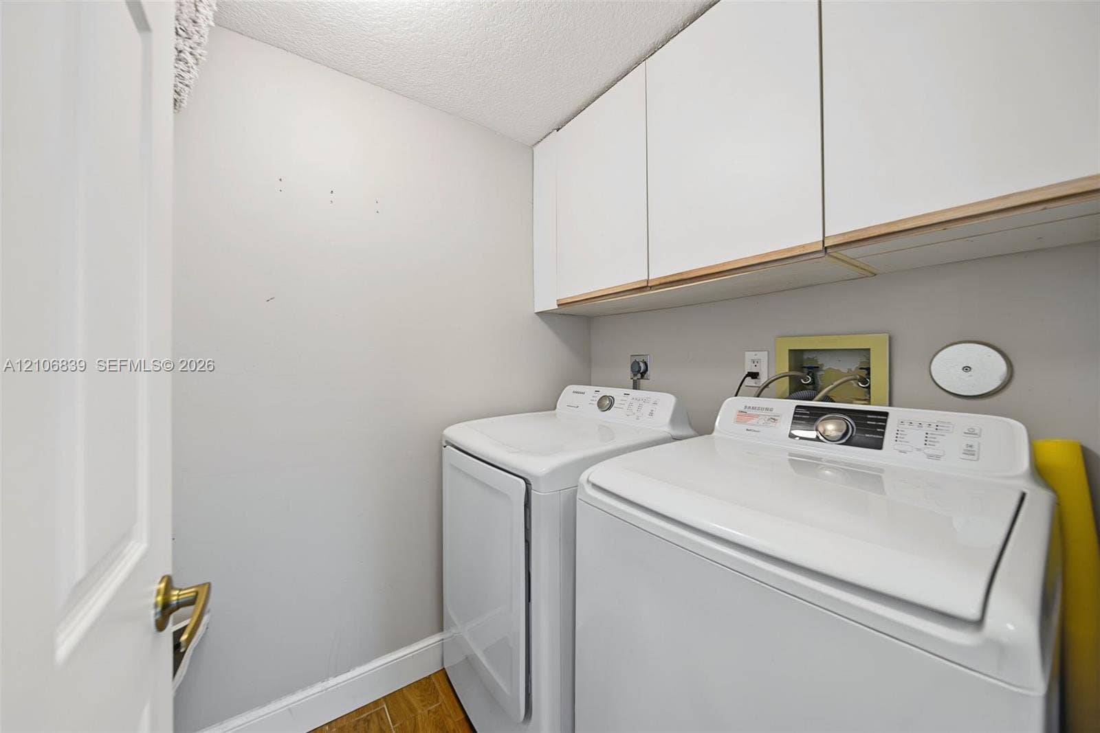 12683 NW 11th Place, Sunrise, FL 33323 Laundry area featuring white cabinetry, wood-finish flooring, and utility hookups