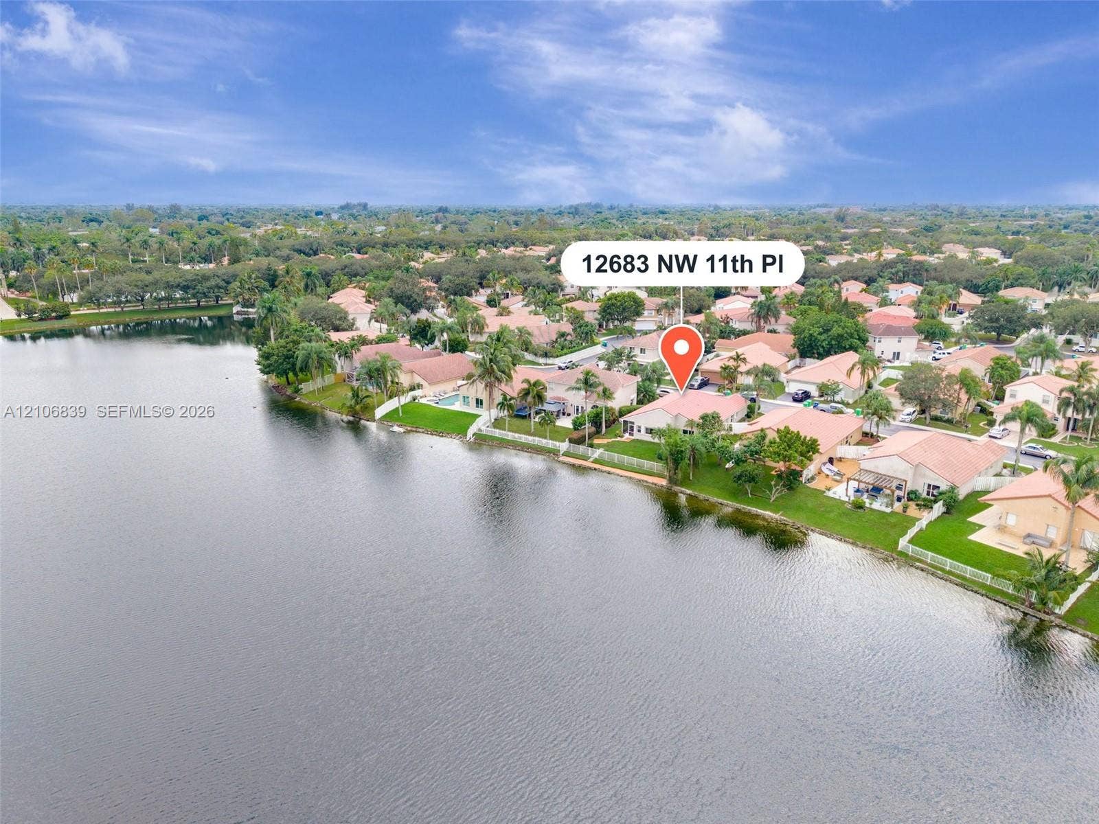 12683 NW 11th Place, Sunrise, FL 33323 Waterfront property featuring a tile-roofed residence, exterior green space, and perimeter fencing