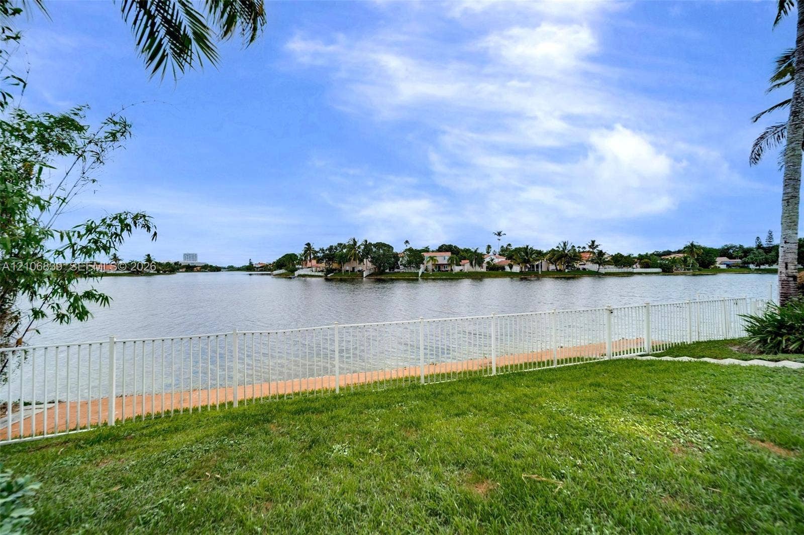 12683 NW 11th Place, Sunrise, FL 33323 Waterfront grounds featuring a grass lawn, metal fencing, and bulkhead