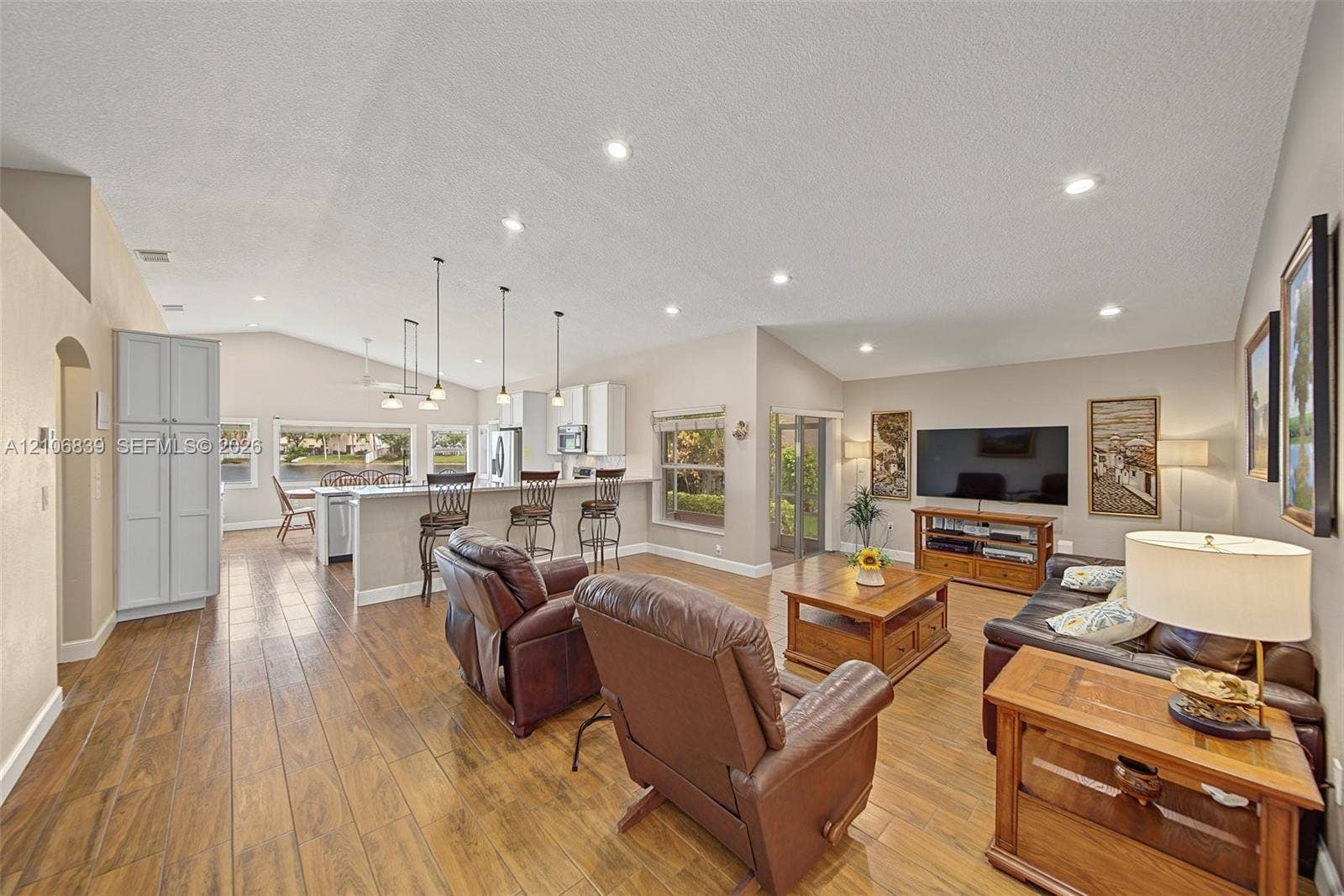 12683 NW 11th Place, Sunrise, FL 33323 Open-concept interior featuring vaulted ceilings, wood-finish flooring, recessed lighting, and a kitchen island with pendant fixtures