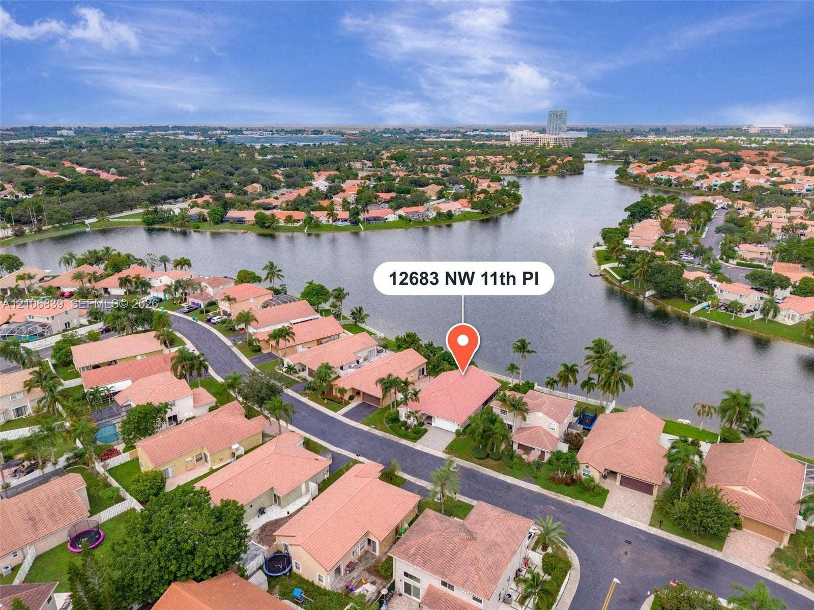 12683 NW 11th Place, Sunrise, FL 33323 Waterfront residence featuring tile roofing, paved driveway, and mature palm trees situated on a canal