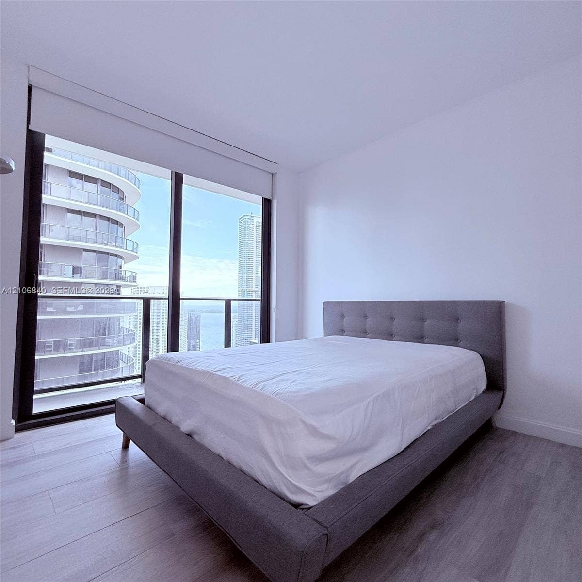 Floor-to-ceiling windows featuring black framing, wood-finish flooring, and an attached balcony with railing