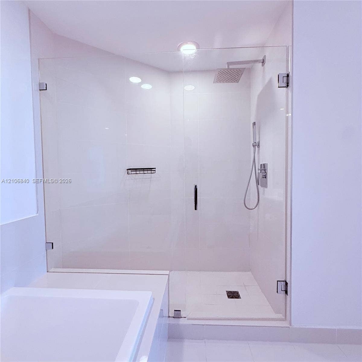 Walk-in shower featuring a frameless glass enclosure, rainfall showerhead, handheld shower attachment, integrated wall niche, and tile flooring