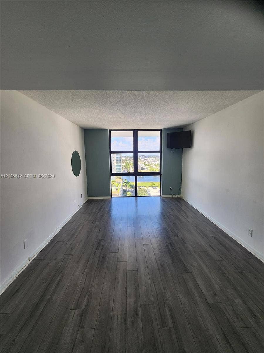 Living area featuring wood-finish flooring, floor-to-ceiling windows, and painted accent walls
