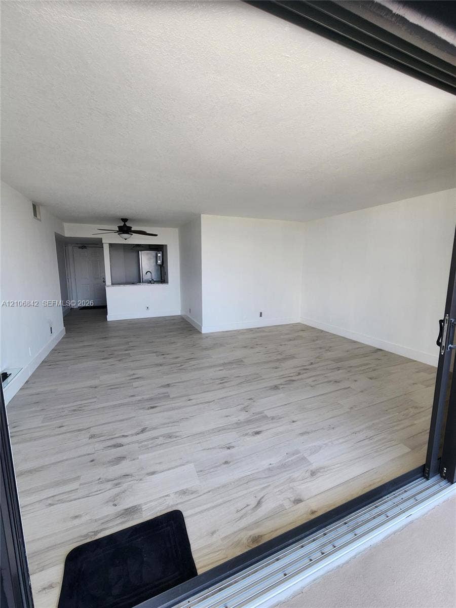 Open interior featuring wood-finish flooring, recessed ceiling lighting, and a pass-through opening to the kitchen