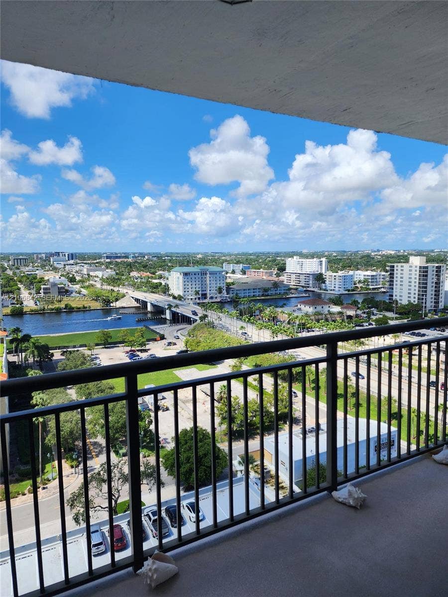 Covered balcony featuring black metal railings and panoramic water and city scenery